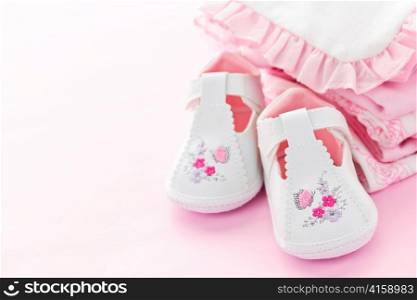 Infant girl clothing and shoes for baby shower on pink background