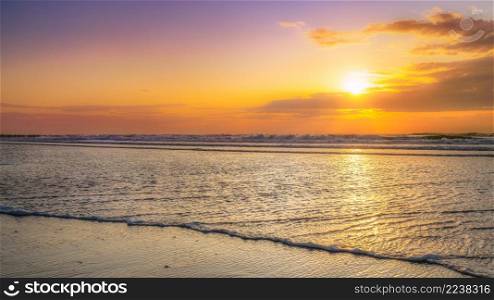 Infinite view of the sea with a cloudy sunset on a sandy beach on the Dutch coast of Zeeland