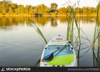 Inflatable stand up paddleboard on calm lake - one of natural areas in Fort Collins, Colorado in late summer scenery