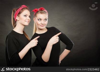 Information and messages. Two blonde pin up retro style women showing something interesting by their fingers. Vintage girls body language.. Pin up vintage ladys showing one direction.