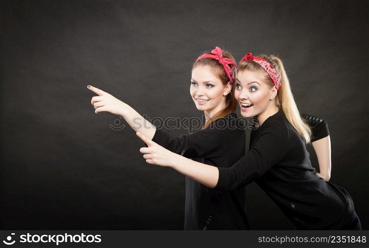 Information and messages. Two blonde pin up retro style women showing something interesting by their fingers. Vintage girls body language.. Pin up vintage ladys showing one direction.