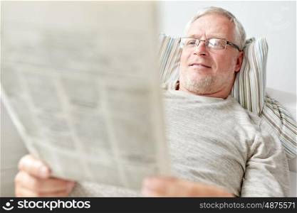information, people, and mass media concept - close up of senior man reading newspaper at home