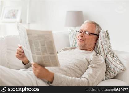 information, people and mass media concept - senior man reading newspaper at home. senior man reading newspaper at home