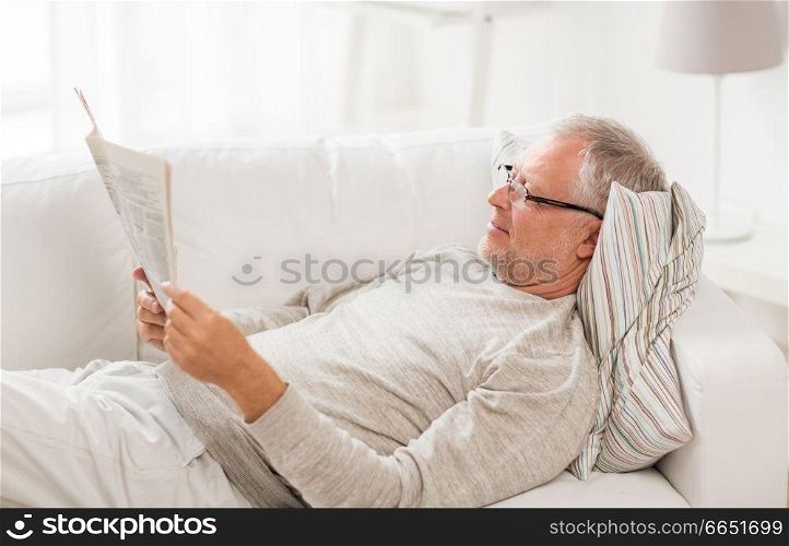 information, people and mass media concept - senior man reading newspaper at home. senior man reading newspaper at home