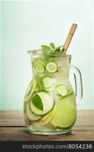 Infused water with cucumber, lemon, lime and mint on blue background