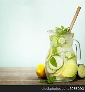 Infused water with cucumber, lemon, lime and mint on blue background