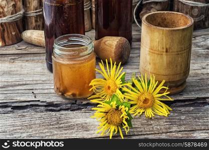 infusion of inflorescences and roots of the medicinal plant Inula on the wooden table next mortar and pestle