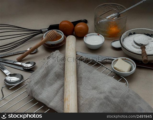Ingredients and kitchen items for baking cakes. flour, eggs, butter, milk and honey on light brown table. Baking background. Selective focus.