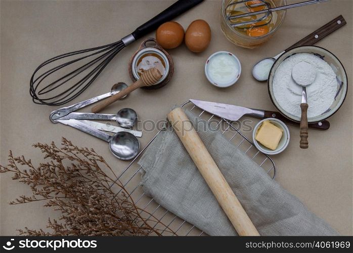 Ingredients and kitchen items for baking cakes. flour, eggs, butter, milk and honey on light brown table. Baking background. Top view, Selective focus.