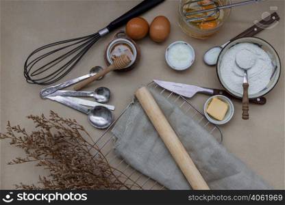 Ingredients and kitchen items for baking cakes. flour, eggs, butter, milk and honey on light brown table. Baking background. Top view, Selective focus.