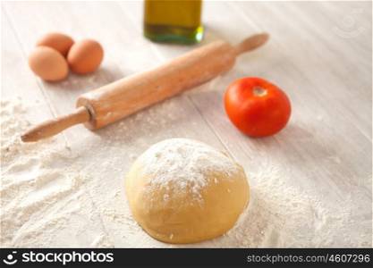 Ingredients and utensils to cook pizza on gray wood board