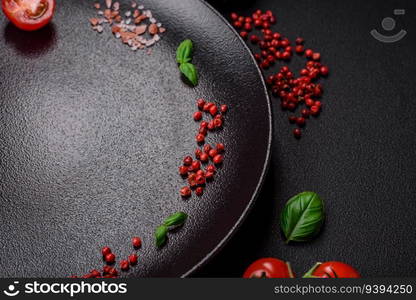 Ingredients for cooking cherry tomatoes, salt, spices and herbs on a dark concrete background