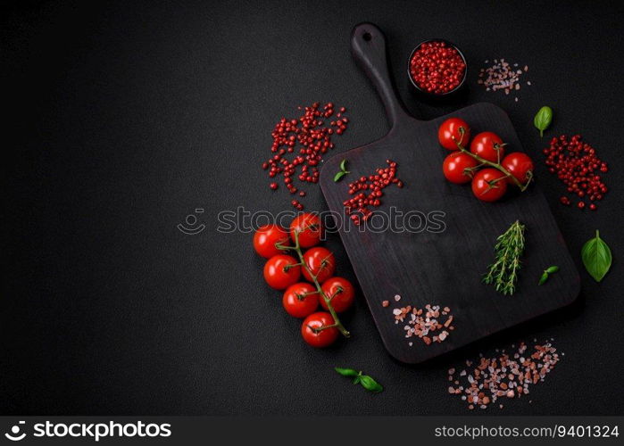 Ingredients for cooking cherry tomatoes, salt, spices and herbs on a dark concrete background