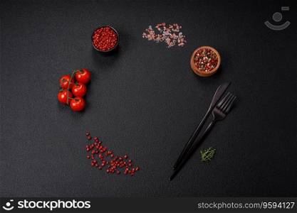 Ingredients for cooking cherry tomatoes, salt, spices and herbs on a dark concrete background