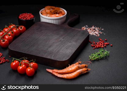 Ingredients for cooking cherry tomatoes, shrimp, salt and spices with a place for an inscription on a dark concrete background. Ingredients for cooking cherry tomatoes, shrimp, salt and spices