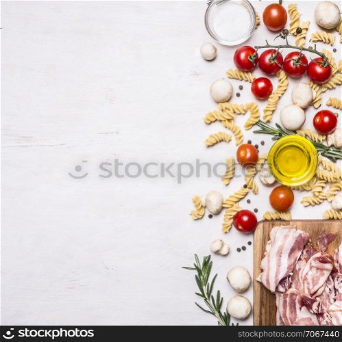 Ingredients for cooking fusilli pasta with bacon vegetables, spices and herbs border, place for text on wooden rustic background top view