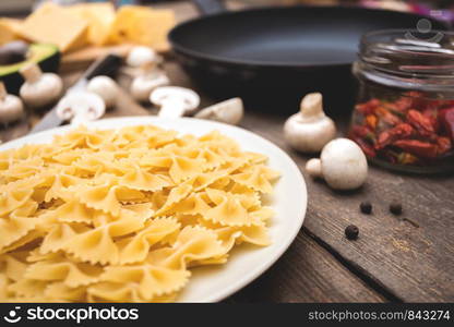 ingredients for cooking italian pasta - pasta, mushrooms, garlic, onions, avocado, cheese and frying pan