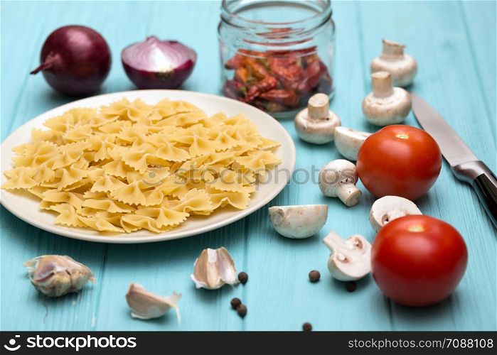 ingredients for cooking italian pasta - pasta, mushrooms, garlic, onions, tomatoes