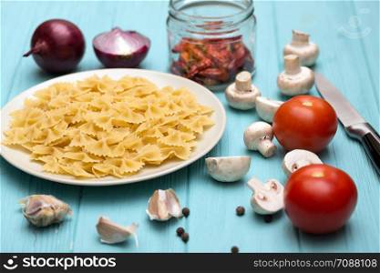 ingredients for cooking italian pasta - pasta, mushrooms, garlic, onions, tomatoes
