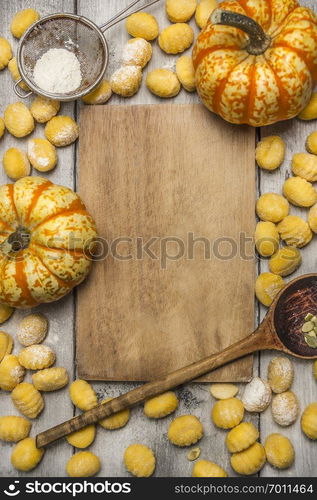 Ingredients for cooking pumpkin gnocchi  flour sieve flour wooden spoon almonds pumpkin, wooden cutting board on wooden rustic background top view