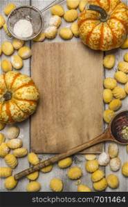 Ingredients for cooking pumpkin gnocchi  flour sieve flour wooden spoon almonds pumpkin, wooden cutting board on wooden rustic background top view
