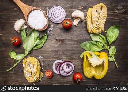 Ingredients for cooking raw pasta with mushrooms, peppers, basil and onions on wooden rustic background top view close up border, place for text