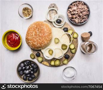 ingredients for homemade burger, tuna, bun, sauce, olives, spices on wooden rustic background top view border, place for text