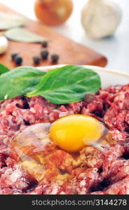 Ingredients for homemade cutlet, ground beef, onion, eggs, pepper, and garlic.