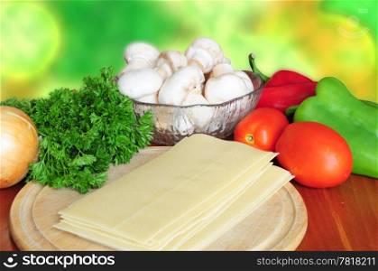 Ingredients for lasagna - tomatoes, pepper, parsley, mushrooms, onion, pasta