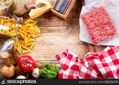 ingredients for pasta with meat sauce on a wooden table