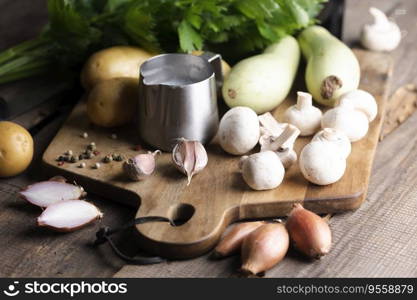 ingredients for soup on a wooden table - potatoes, cream, zucchini, onion, celery
