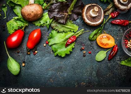 Ingredients for tasty salad making: lettuce leaves,champignons, tomatoes, herbs and spices on dark rustic background, top view, border. Healthy, diet or vegetarian food concept.