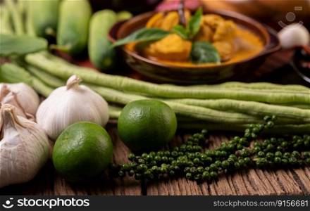 Ingredients with lemon, garlic, long beans, and fresh pepper seeds on a wooden table