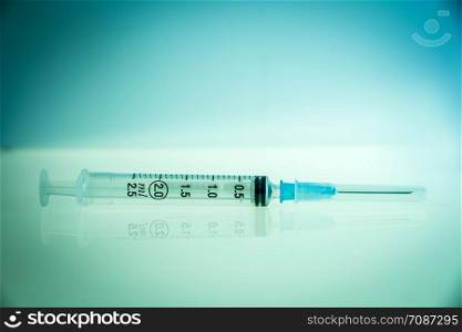Injection syringe on a clean blue background. Syringe on blue background