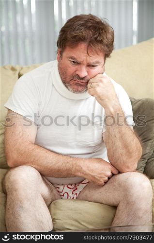 Injured man wearing a neck brace, suffering from depression, home alone in his underwear.