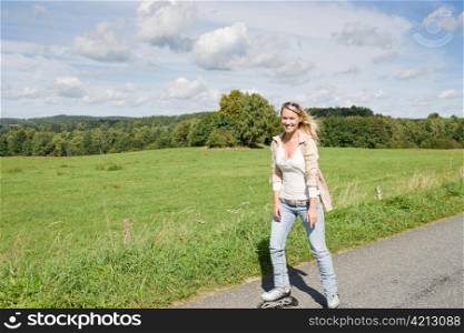 Inline skating young woman wearing jeans on sunny asphalt road