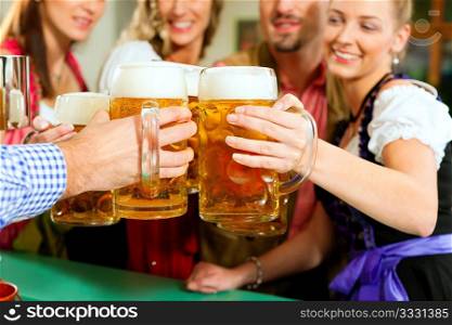 Inn or pub in Bavaria - group of young men and women in traditional Tracht drinking beer and having a party with beer