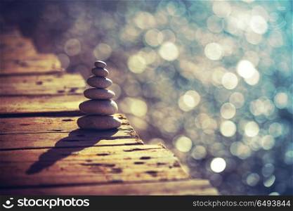 Inner peace and balance, pile of pebbles on the wooden bridge on the beach, summer vacation on the spa resort, life and harmony concept. Inner peace and life in balance concept
