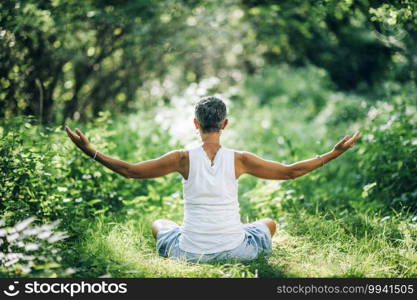 Inner peace meditation. Mindful woman meditating with open arms, sitting on the ground, surrounded by beautiful nature nurturing and increasing sense of inner peace . Inner Peace Meditation, Embracing the Nature
