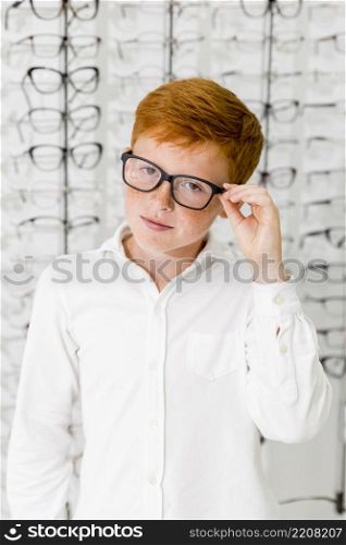 innocent boy with black frame spectacle standing optics store