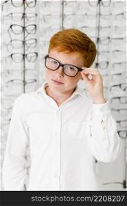innocent boy with black frame spectacle standing optics store