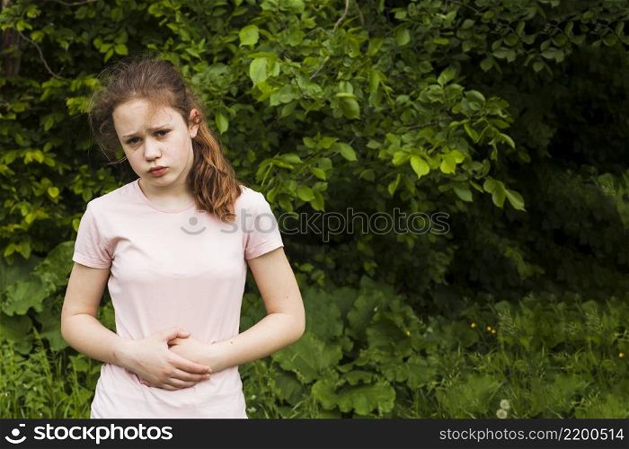 innocent girl holding her stomach while having stomach pain park