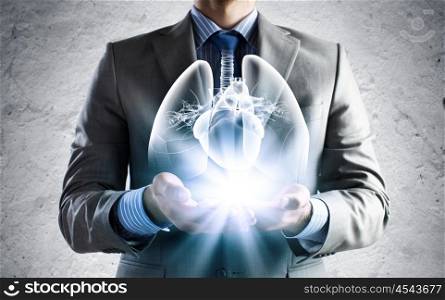 Innovation in medicine. Close up of businessman holding image of lungs in hands