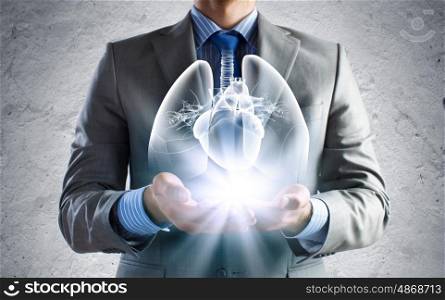 Innovation in medicine. Close up of businessman holding image of lungs in hands