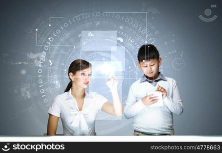 Innovation technologies in education. Woman teacher and boy at lesson touching media screen