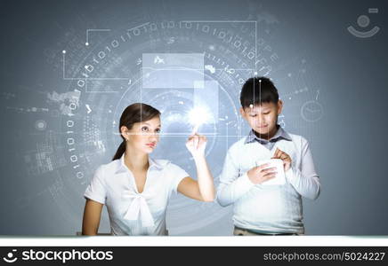 Innovation technologies in education. Woman teacher and boy at lesson touching media screen