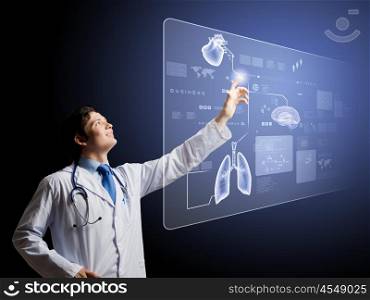 Innovations in medicine. Young male doctor touching icon on media screen