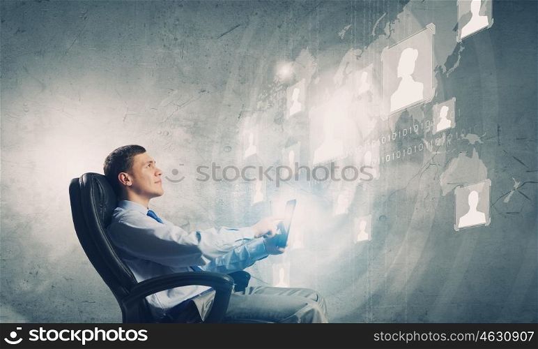 Innovative technologies. Young businessman with tablet in hands against digital background