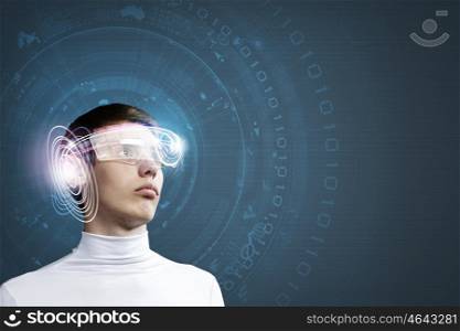 Innovative technologies. Young man wearing futuristic glasses against blue background