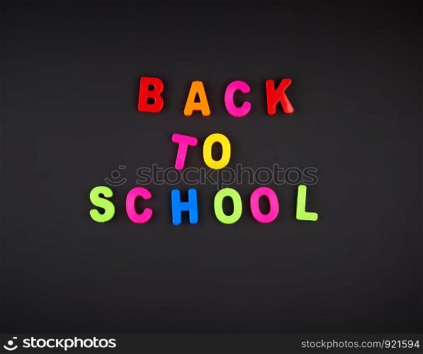 inscription back to school from multi-colored plastic letters on black chalk board, concept back to school